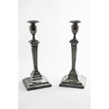 A PAIR OF GEORGE III CANDLESTICKS on bevelled square bases with tapering fluted columns, vase-shaped