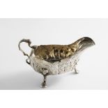 A LATE GEORGE II IRISH SAUCE BOAT on three cast scroll feet with human mask knuckles and a lion mask