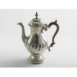 A LATE GEORGE II COFFEE POT of baluster form with wrythen fluting around the lower body, foot and