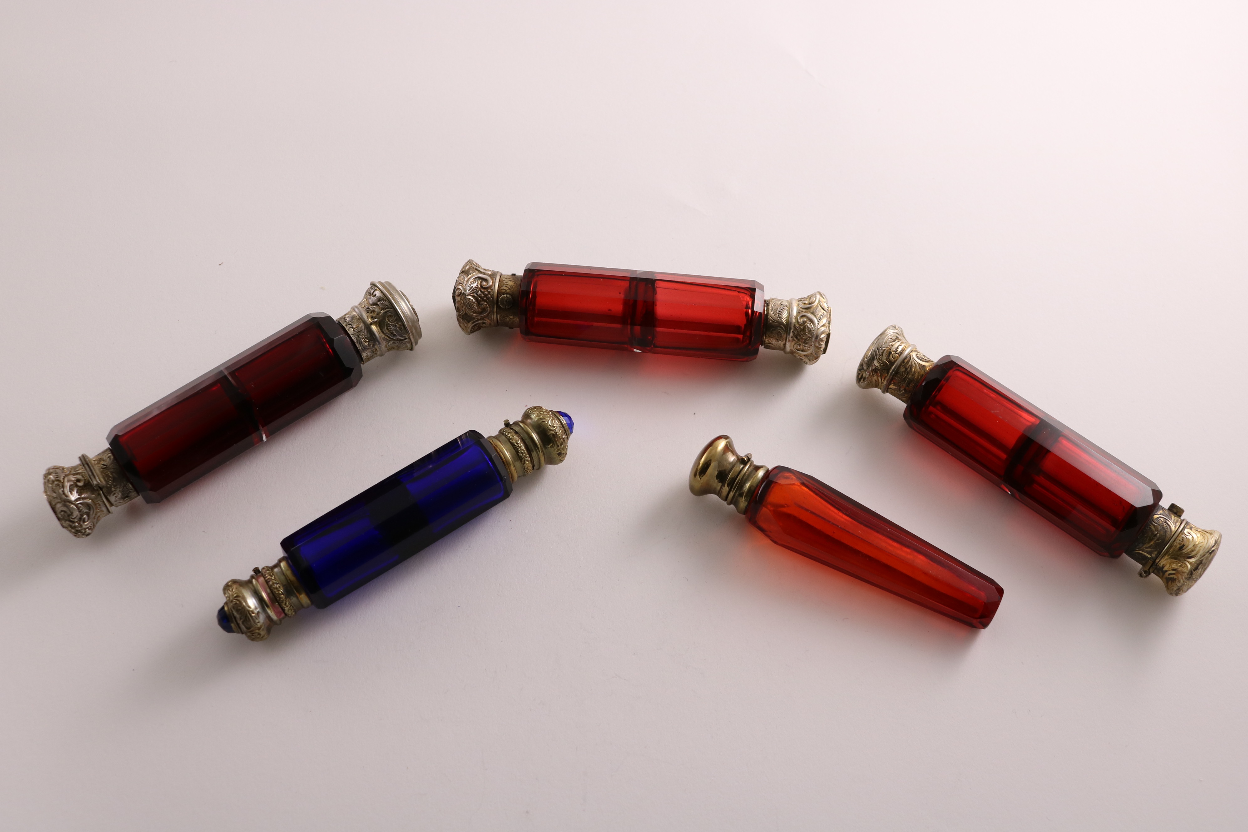 THREE VICTORIAN SILVERGILT-MOUNTED DOUBLE-ENDED RED GLASS SCENT BOTTLES and two brass-mounted