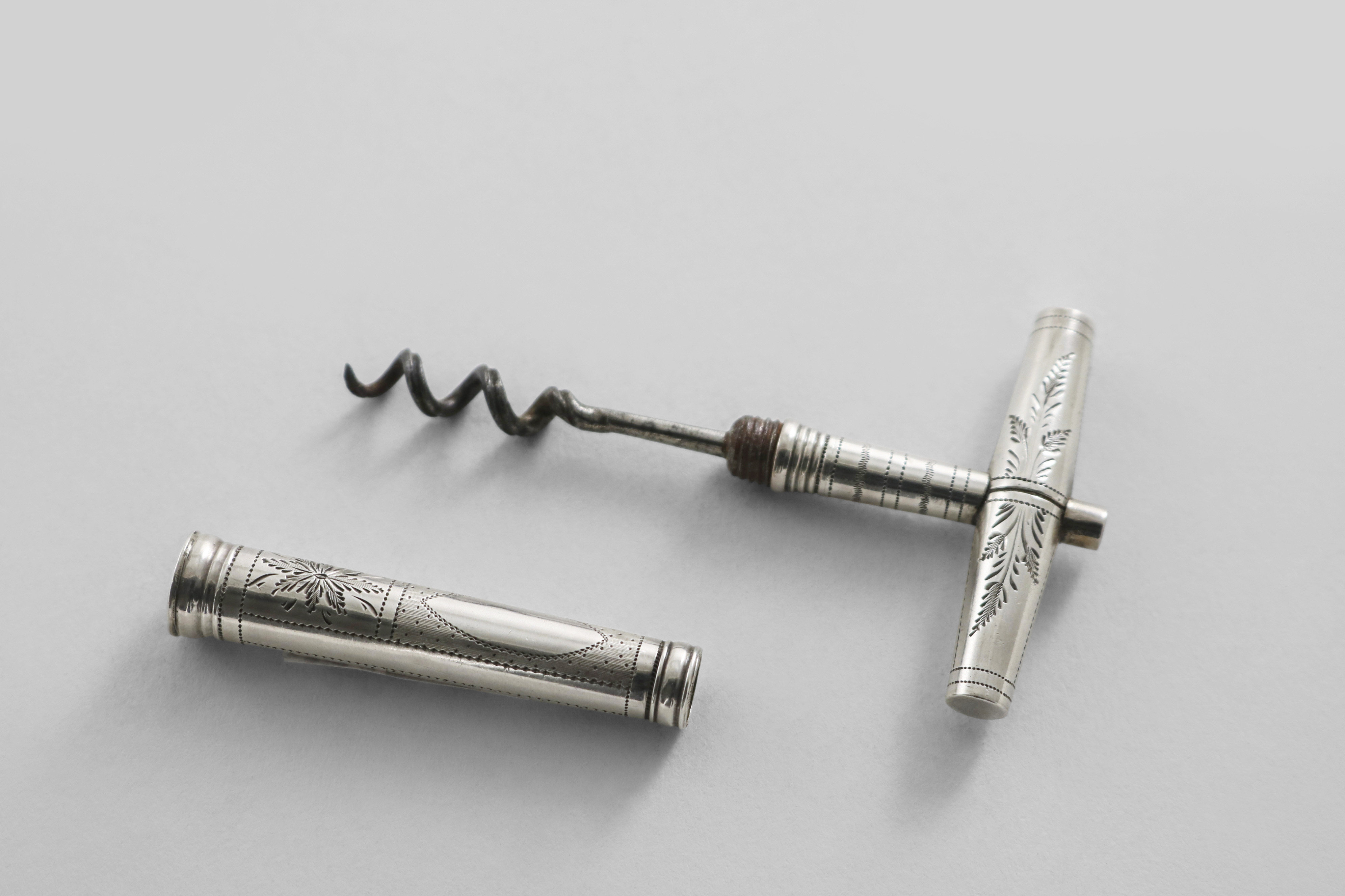 A GEORGE III POCKET CORKSCREW with a steel worm, a T-shaped handle and a tapering screw cover, the