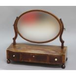 GEORGE III MAHOGANY AND INLAID TOILET MIRROR, the oval mirror on a shaped rectangular base with