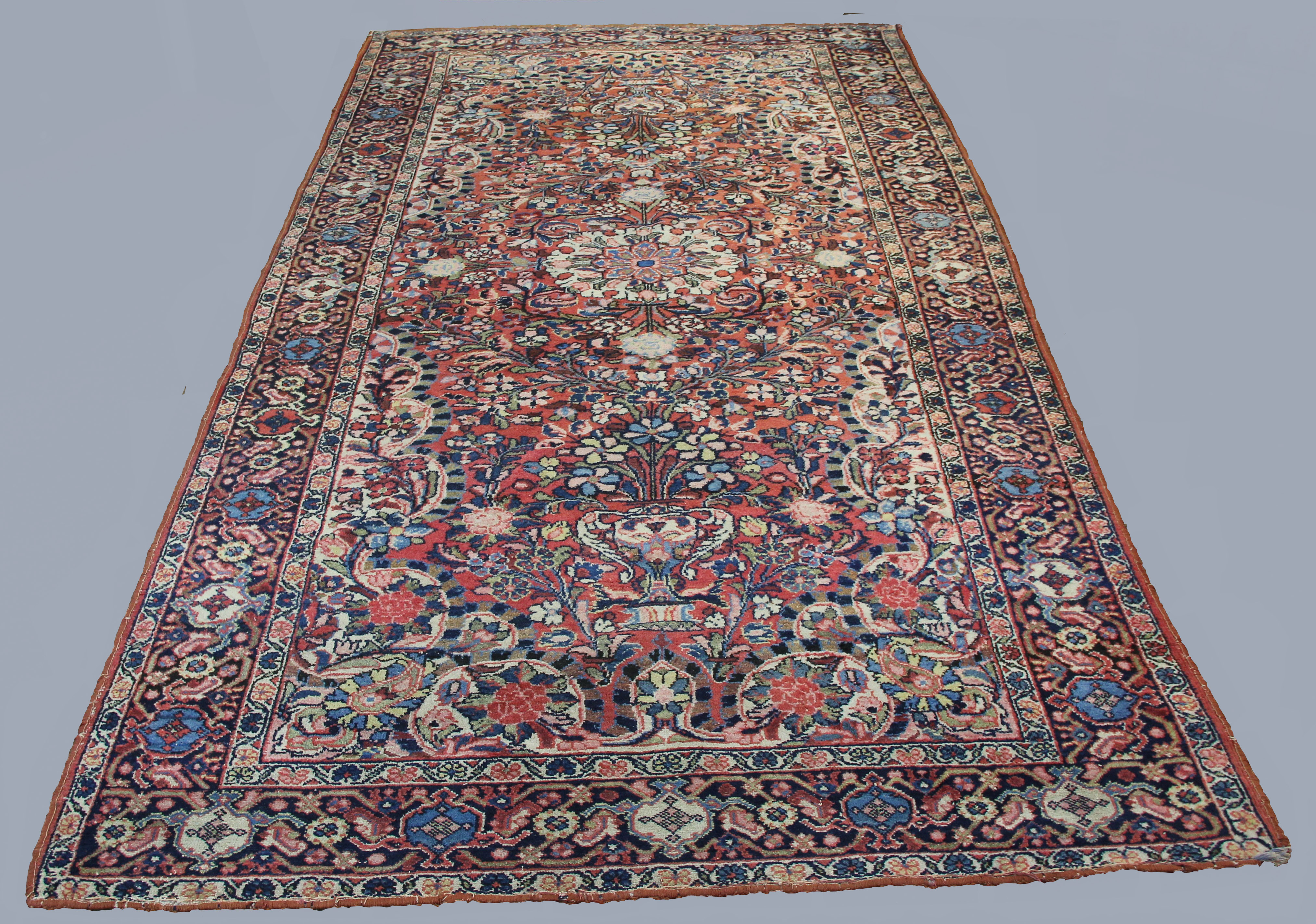 FERAGHAN CARPET, West Iran, circa 1925, the terracotta field with urns issuing flowers centred by an