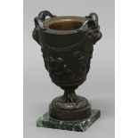 BRONZE URN OR OIL LAMP BASE, 19th century, cast with putti playing beneath goats head handles,