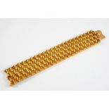 A YELLOW GOLD STRAP BRACELET formed with articulated conical shaped links, with concealed clasp,