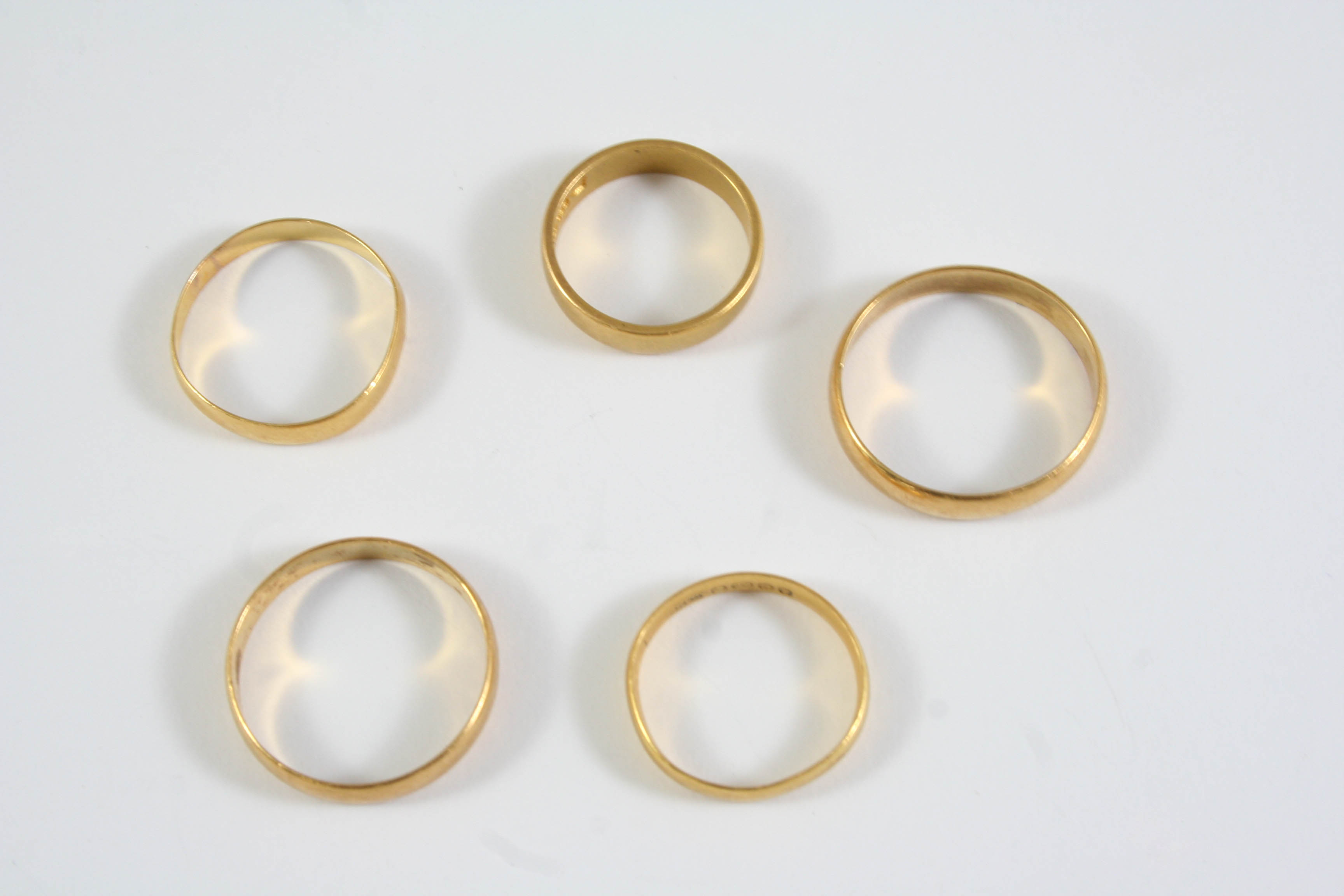 THREE 22CT GOLD WEDDING BANDS 8.6 grams, together with two unmarked gold wedding bands, 6.6 grams