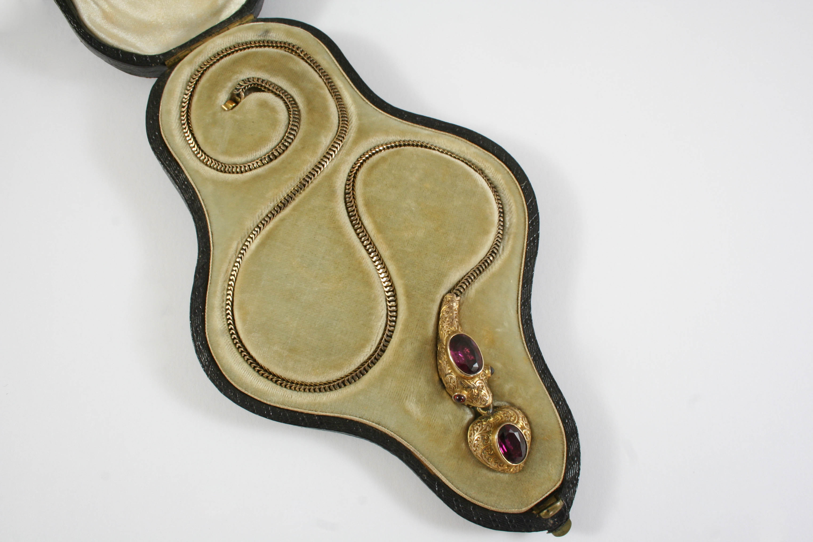 A VICTORIAN GARNET AND GOLD SNAKE NECKLACE the gold foliate engraved head mounted with an oval