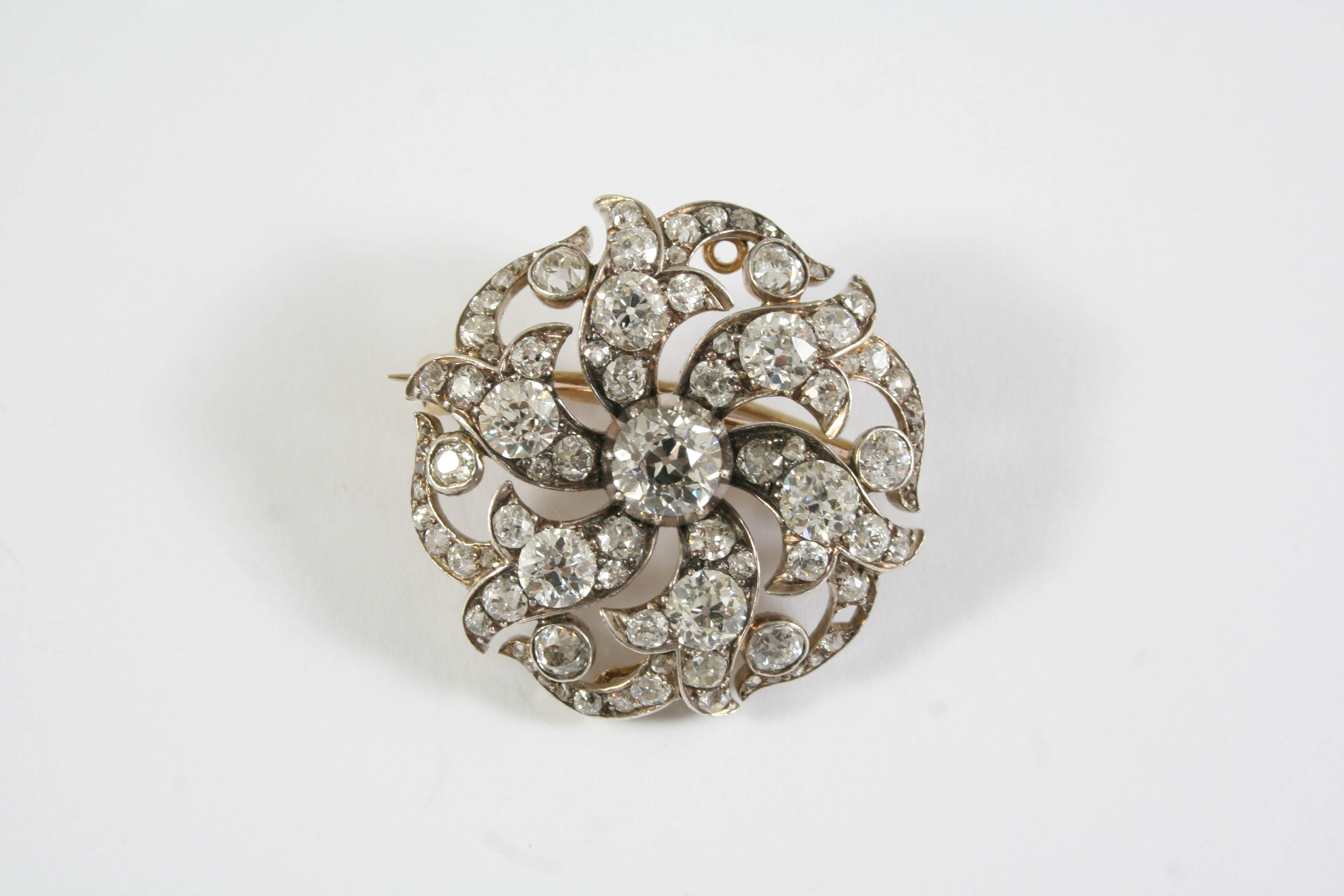 A VICTORIAN DIAMOND BROOCH PENDANT of circular foliate form, set overall with graduated old