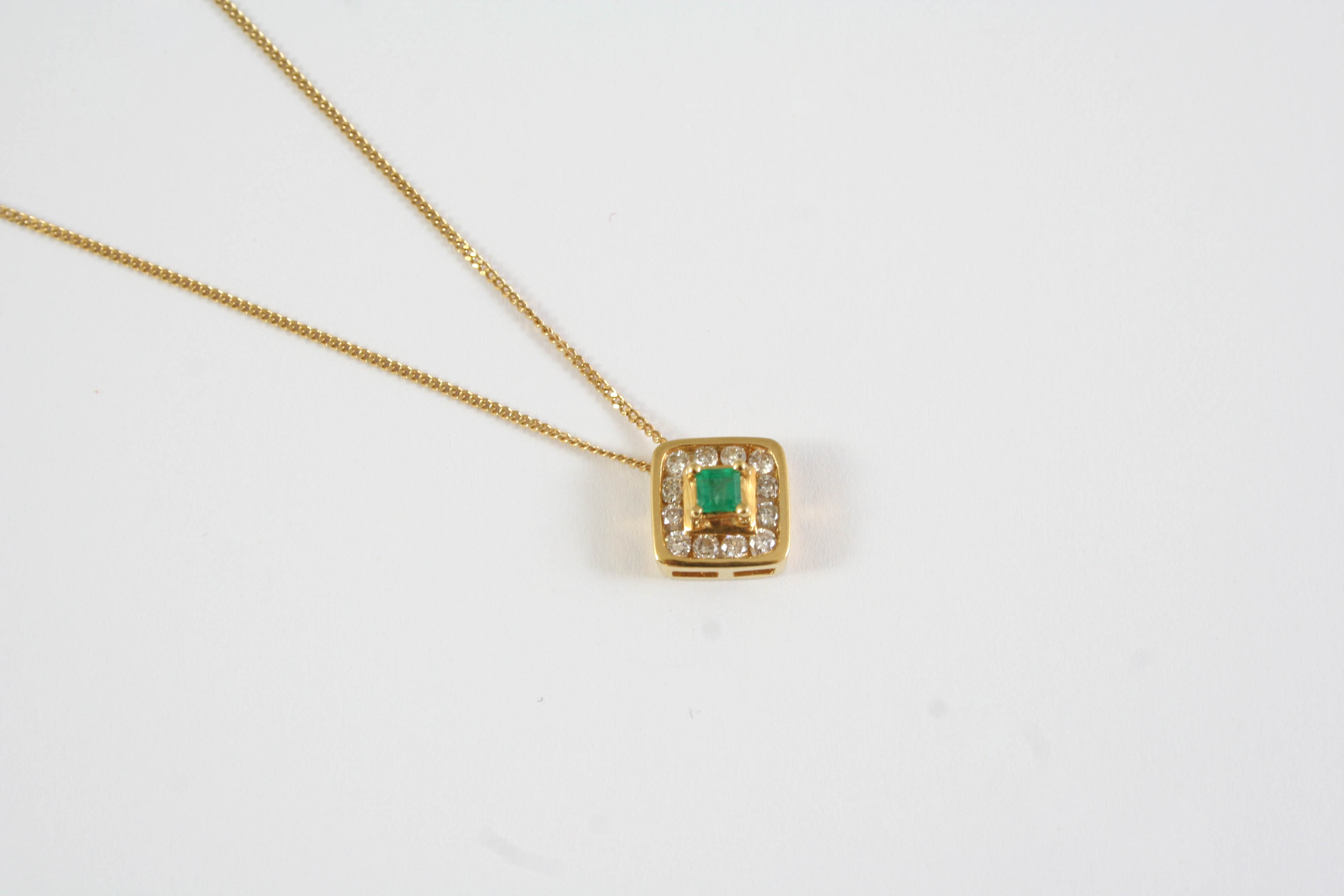 AN EMERALD AND DIAMOND CLUSTER PENDANT the square-shaped emerald is set within a surround of