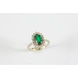 AN EMERALD AND DIAMOND CLUSTER RING the oval-shaped emerald is set within a surround of two