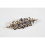AN EDWARDIAN SAPPHIRE AND DIAMOND BROOCH of openwork scrolling foliate design mounted with oval-
