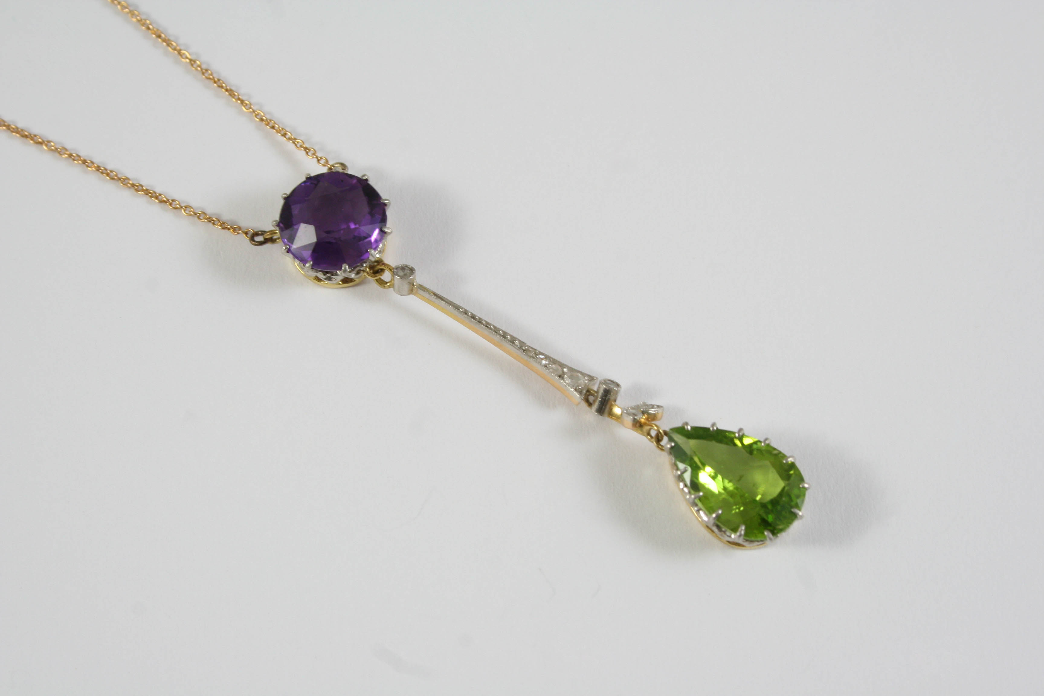 AN EDWARDIAN SUFFRAGETTE PENDANT the pear-shaped peridot is suspended from a foliate design set with