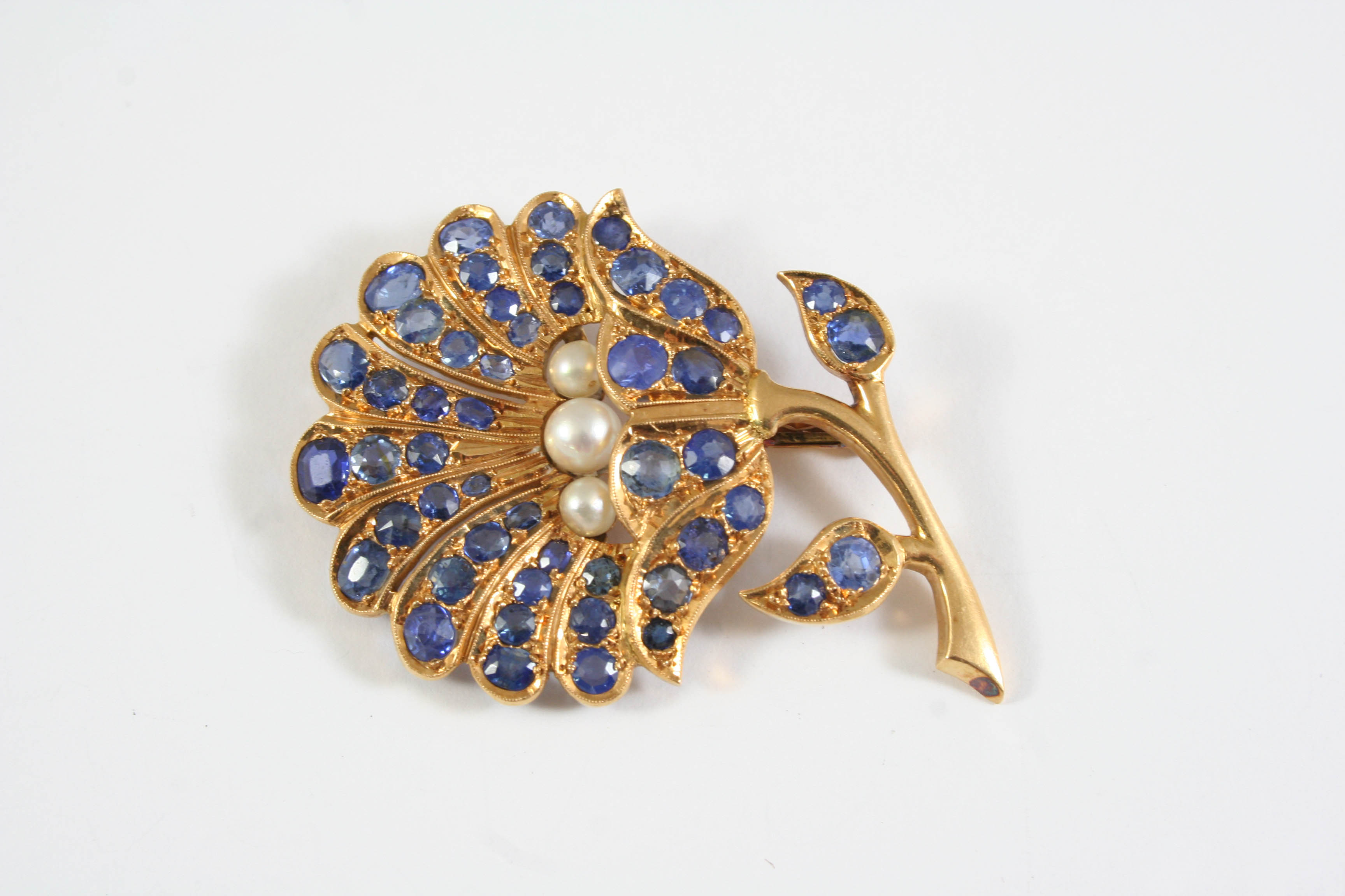 A SAPPHIRE, CULTURED PEARL AND GOLD FOLIATE BROOCH mounted with three cultured pearls and overall