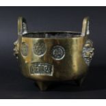 CHINESE BRASS TRIPOD CENSER, stamped with various roundels and panels between two lion heads and