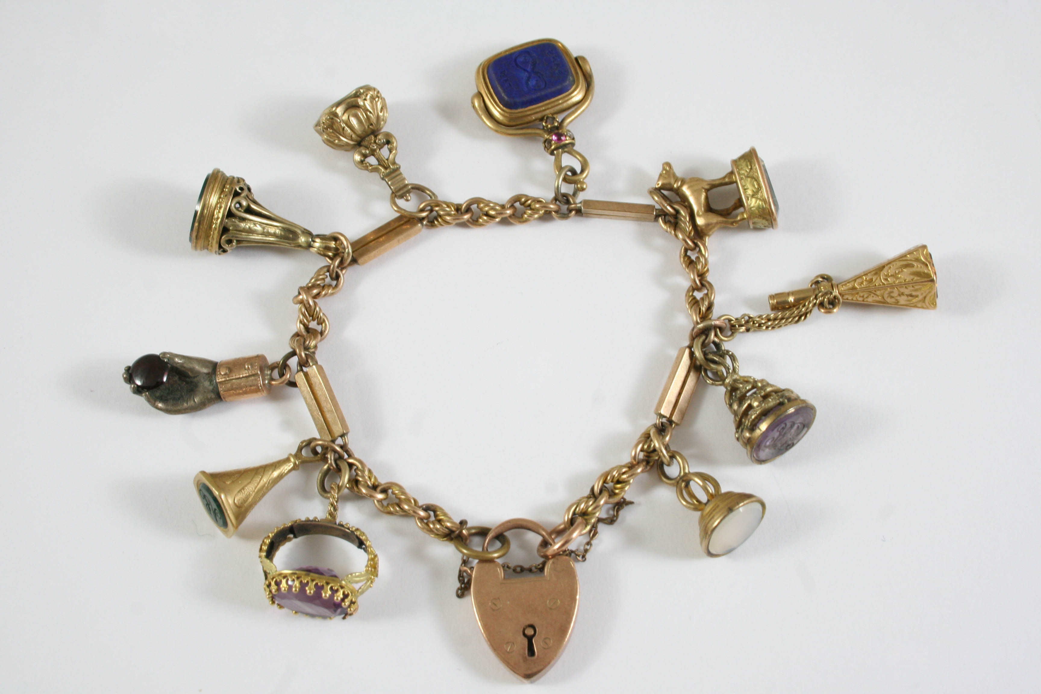 A GOLD CHARM BRACELET formed alternately with rope twist and solid gold links, with padlock clasp