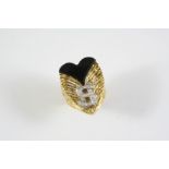 AN 18CT GOLD, BLACK ONYX AND DIAMOND RING BY KUTCHINSKY designed as a stylised heart with a dollar