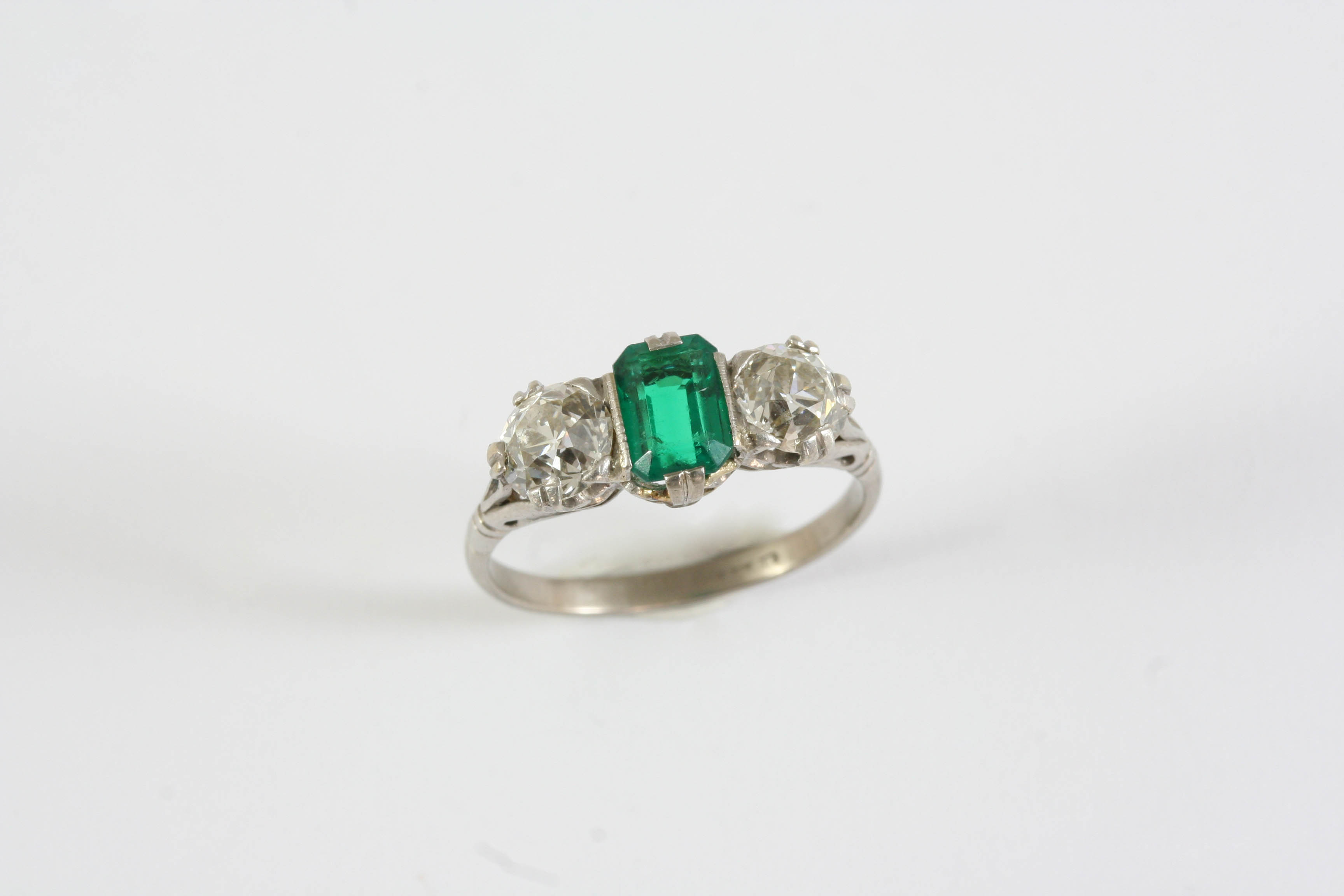 AN EMERALD AND DIAMOND THREE STONE RING the rectangular-shaped emerald is set with two old cushion-