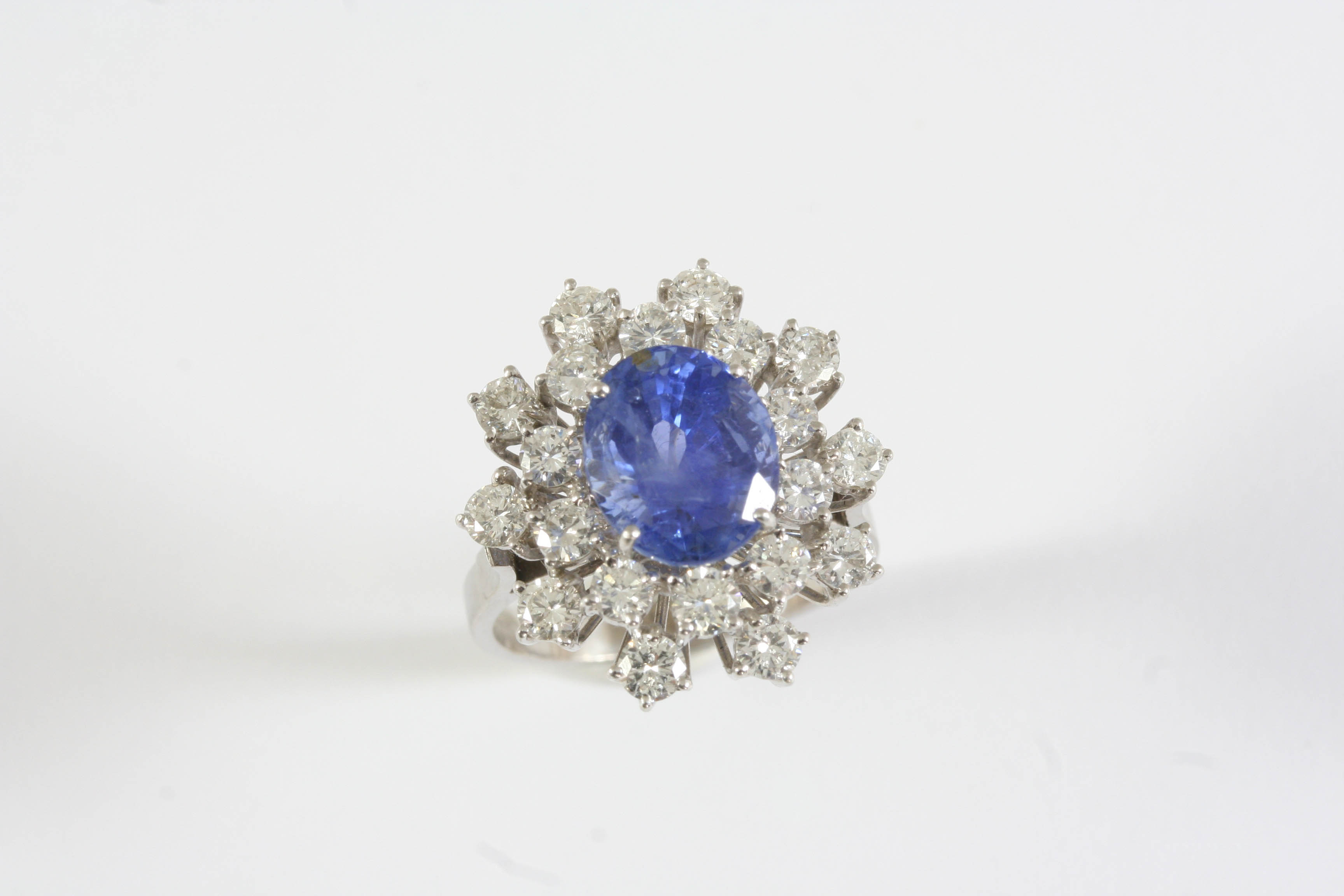 A SAPPHIRE AND DIAMOND CLUSTER RING the oval-shaped sapphire is set within a surround of round