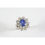 A SAPPHIRE AND DIAMOND CLUSTER RING the oval-shaped sapphire is set within a surround of round