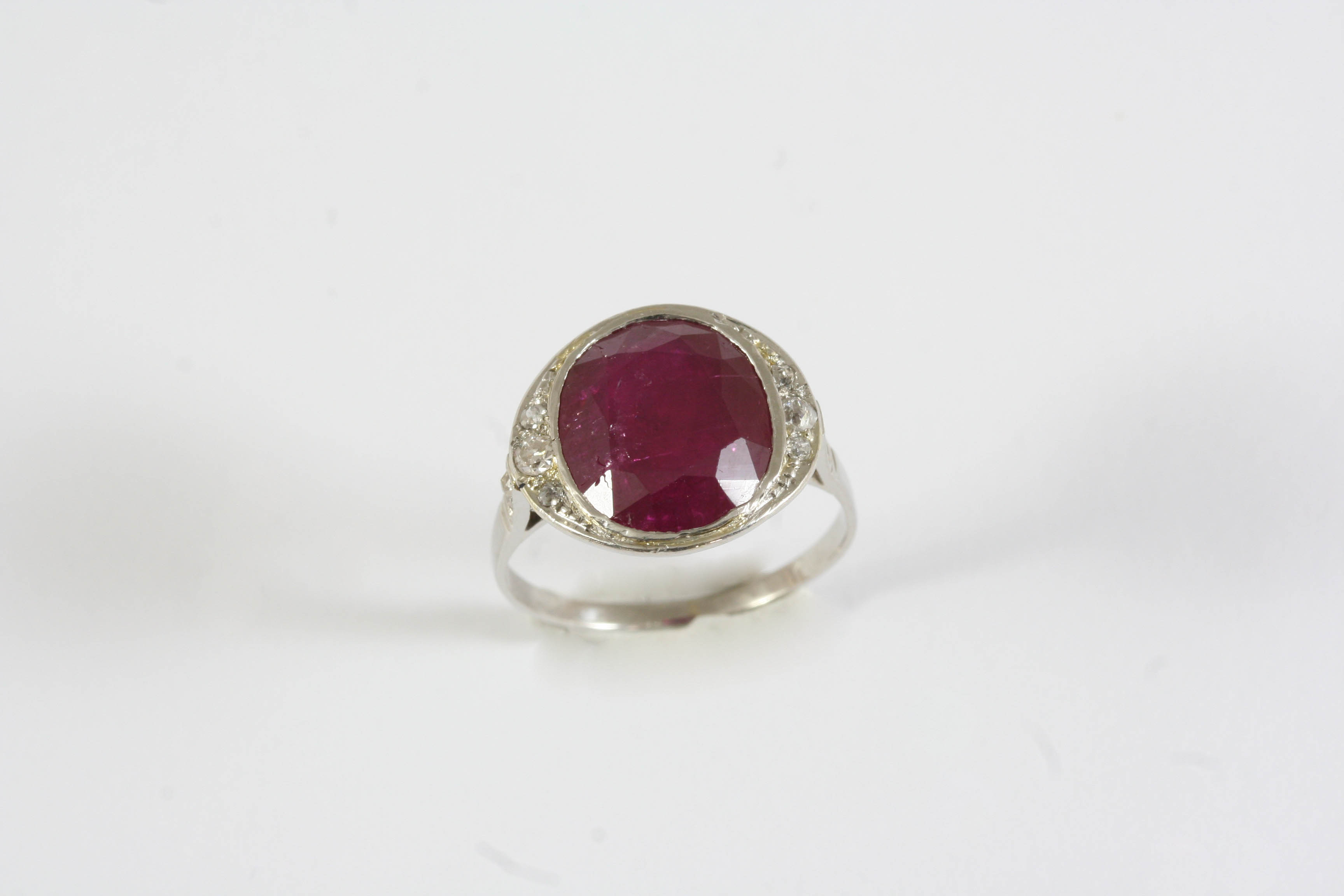 A RUBY AND DIAMOND RING the oval-shaped ruby weighs 6.21 carats and is set with graduated old