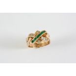AN EMERALD AND DIAMOND RING formed with a row of calibre-cut emeralds and interlocking sections of