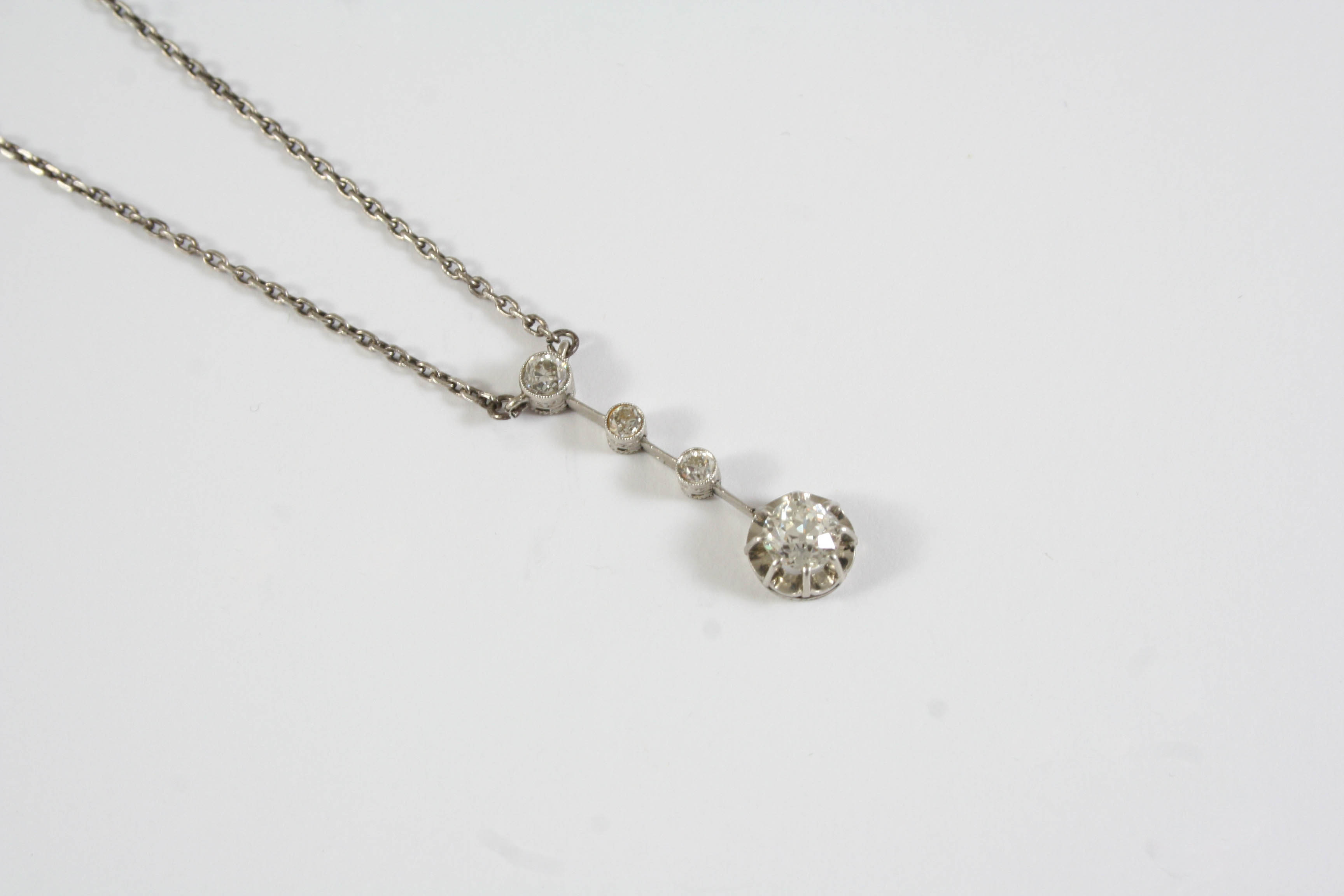 A DIAMOND PENDANT the old cushion-shaped diamond drop is claw set and suspended from a knife edge