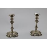 A PAIR OF GEORGE II CAST CANDLESTICKS on shaped quatrefoil bases with moulded borders and "well"