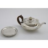 A GEORGE III PART-FLUTED CIRCULAR TEA POT with a "cape" rim and an ivory finial, crested, by William