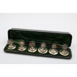 AN EDWARDIAN CASED SET OF SIX MENU CARD HOLDERS on domed circular bases, each with vignette,