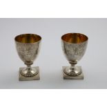 A PAIR OF GEORGE III GOBLETS on square pedestal bases with gadrooning, gilt interiors, crested, by