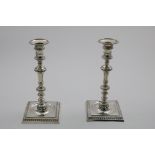 A PAIR OF LATE GEORGE II CAST CANDLESTICKS with knopped columns and square bases with "well" centres