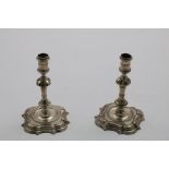 A GEORGE II MATCHED PAIR OF GEORGE II CAST TAPERSTICKS on shaped square bases with knopped and