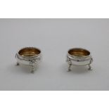 A PAIR OF GEORGE IV SQUAT CIRCULAR SALTS on three legs with shaped gadrooned rims and gilt