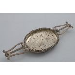 A GEORGE III SCOTTISH LEMON STRAINER (for a punch bowl) with twin lyre handles, each decorated
