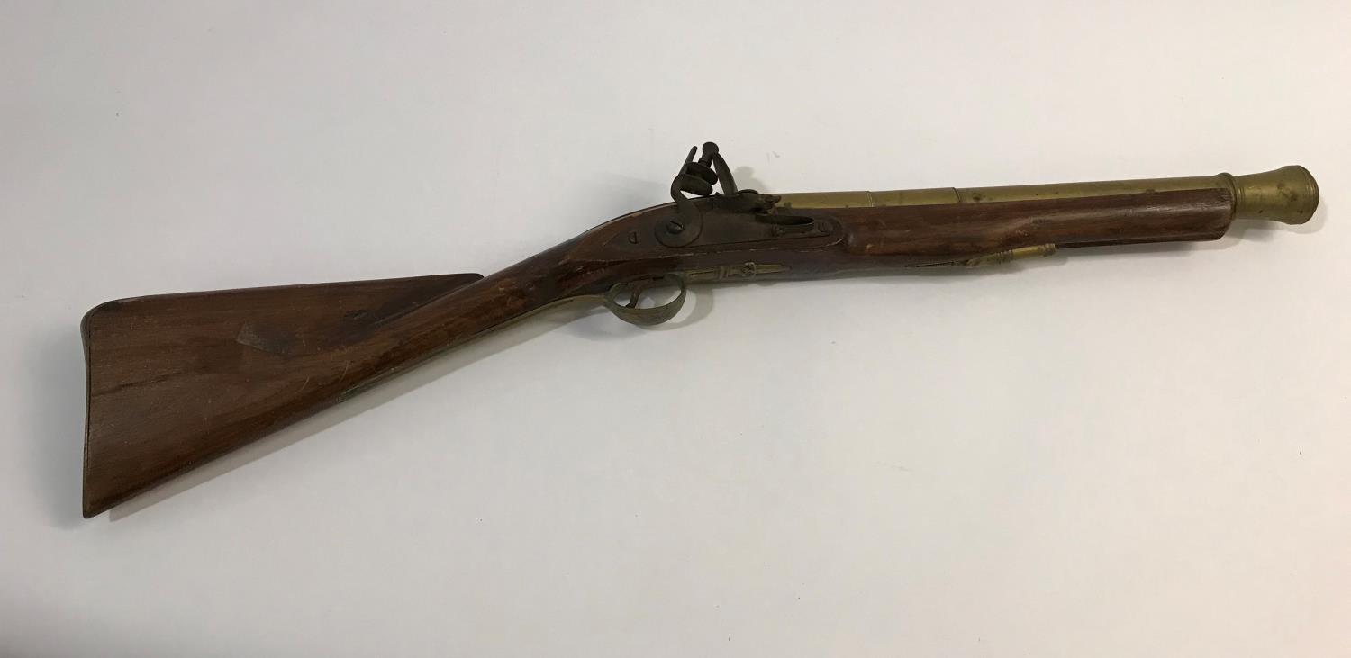 A FLINTLOCK BLUNDERBUSS. A flintlock blunderbuss with flared brass barrel, top mounted sprung