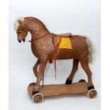 VINTAGE PULL ALONG HORSE a pony skin pull along horse, fitted with a saddle and mounted on a painted