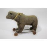 VINTAGE PULL ALONG BEAR possibly by Steiff, the Bear mounted on a metal frame and wooden wheels.