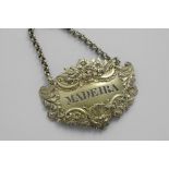 A GEORGE IV SILVERGILT, ESCUTCHEON-SHAPED WINE LABEL with a raised border of flowers, shells and