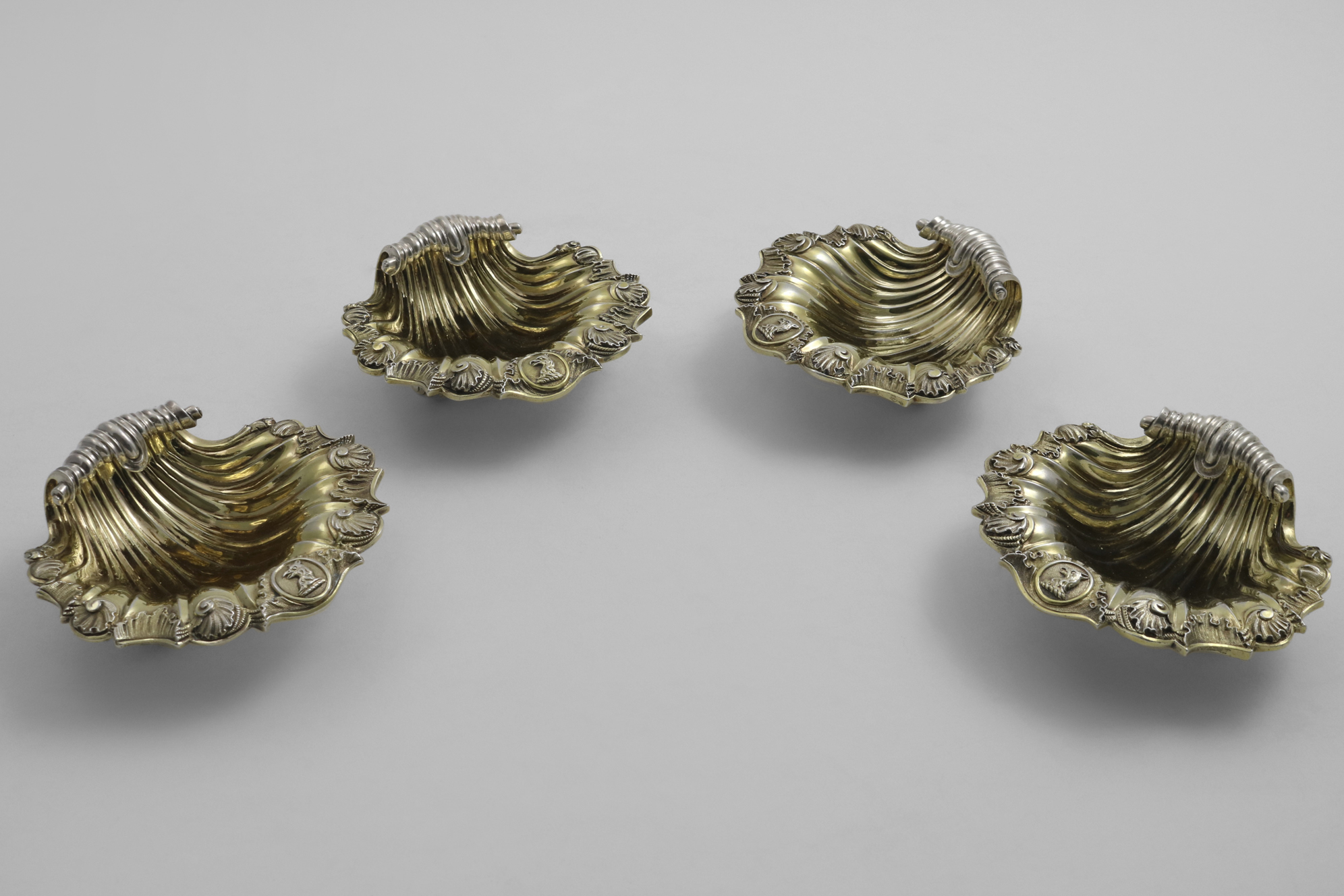 A SET OF FOUR EARLY VICTORIAN CAST SCALLOP SHELL SALTS with a chased border around the rim