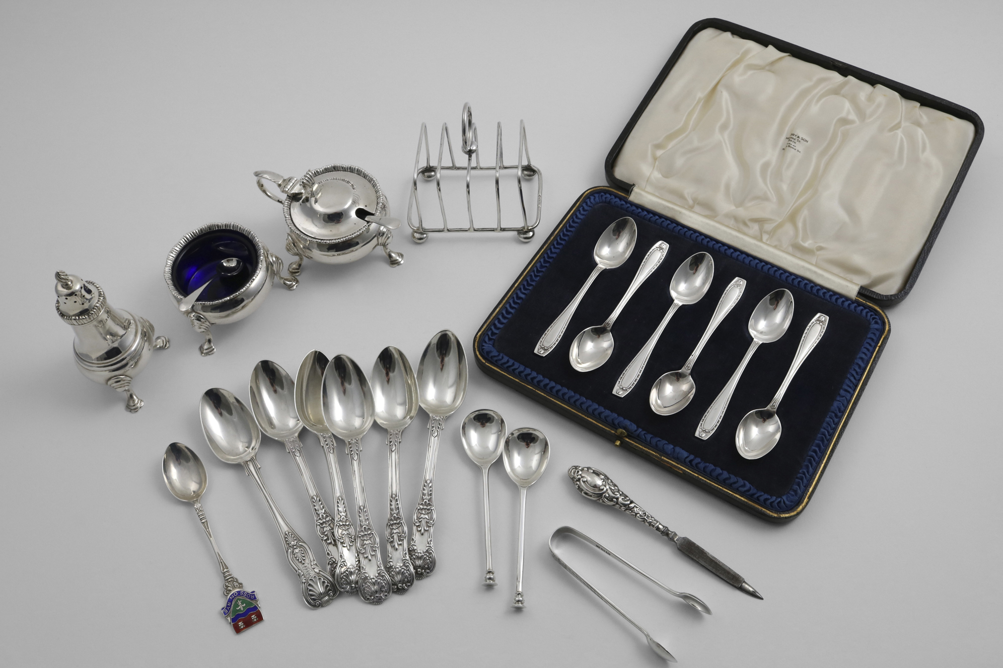 A MIXED LOT:- A cased set of six tea spoons, a three-piece circular condiment set with blue glass