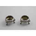 A PAIR OF VICTORIAN CIRCULAR SALTS on three lion mask & paw feet, with repousse-work decoration