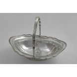 A GEORGE III CAKE BASKET of shaped oval outline with a reeded border & swing handle, engraved border