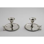 A PAIR OF EARLY VICTORIAN CHAMBERSTICKS on shaped circular bases with gadrooned borders, leaf-capped