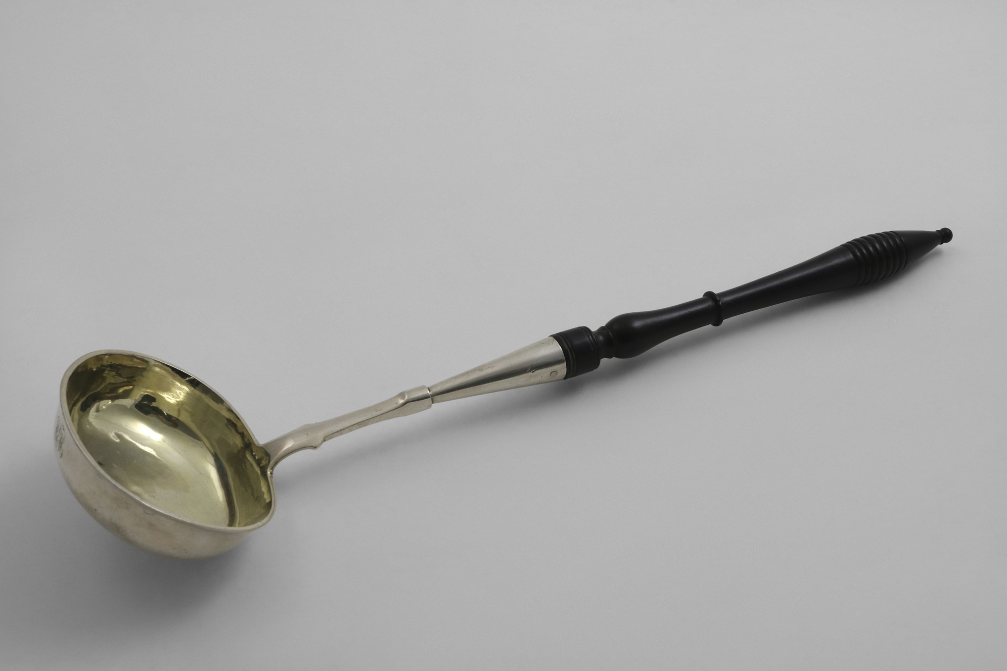 A MID 19TH CENTURY RUSSIAN LADLE with a turned hardwood handle, an oval bowl with gilt interior,