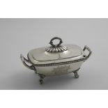 A GEORGE III TWO-HANDLED SAUCE TUREEN & COVER on four leafy scroll feet with a gadrooned border