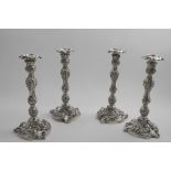 A SET OF FOUR GEORGE IV ROCOCO REVIVAL CAST CANDLESTICKS on shaped tricorn bases, decorated in