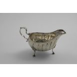 GEORGE III IRISH SAUCE BOAT on three legs with chased fluting and bead borders, the cartouche