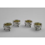 A SET OF FOUR EARLY VICTORIAN SALTS of shaped circular outline on three decorative scroll feet