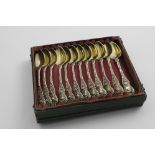 A CASED SET OF TWELVE MID 19TH CENTURY FRENCH SILVERGILT TEA SPOONS with naturalistic decorations,