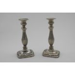 A PAIR OF LATE VICTORIAN CANDLESTICKS on rounded oblong bases, decorated in relief with part-fluting